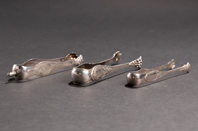 trois cuillères en argent et un repose-cuillère posés sur une surface noire