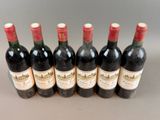 six bottles of red wine lined up in a row on a table