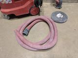 a vacuum and a hose on the floor in a garage