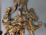 a gold statue on the wall next to a candle