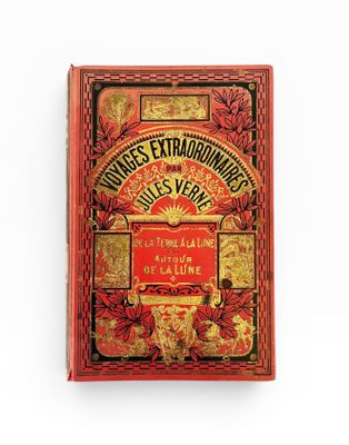 un vieux livre à la couverture rouge posé sur une surface blanche