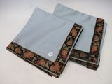 two folded napkins on a white table with a black and gold border