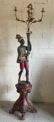 a statue of a man holding a candelab on a pedestal