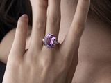 someone is wearing a ring with a purple stone in it