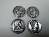 four silver coins with heads of men on them sitting on a table
