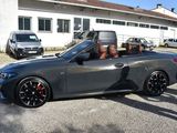 a man sitting in the driver ' s seat of a convertible car