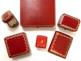 une boîte rouge sur laquelle sont représentés un stylo, un crayon, des gommes et d'autres objets