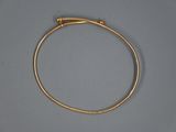 gros plan d'un bracelet en or sur une surface grise