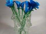 a vase with blue flowers in it on a white surface