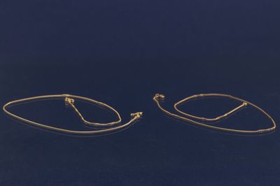 une paire de boucles d'oreilles créoles en or sur fond bleu
