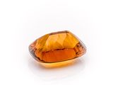 a close up of an orange sapphire stone on a white surface