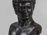 a bronze bust of a young man with curly hair