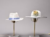 two hats on a table with a lamp on top of them