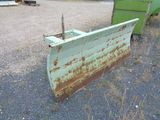 a rusted green plow sitting in the dirt