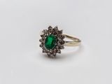 gros plan d'une bague avec une pierre verte entourée de diamants blancs