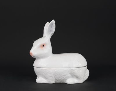 un lapin en porcelaine blanche posé sur une surface noire