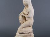 une statue de femme assise au sommet d'un rocher