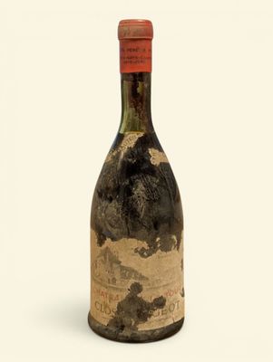 une vieille bouteille de vin posée sur une surface blanche