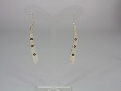 silver earrings with brown stones on them on a clear stand