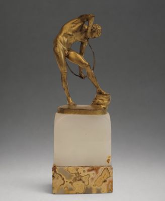 une image représentant une statue d'un homme tenant une raquette de tennis, posée sur un socle en marbre