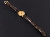 a gold plated wrist watch on a black background
