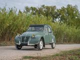 a small green car driving down a dirt road