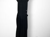 black dress hanging on a hanger next to a vase of flowers