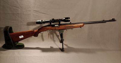 the rifle is sitting on a stand with a scope on it