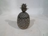 un ananas argenté posé sur une surface blanche