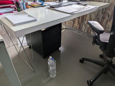 a desk with a computer and a bottle of water on it