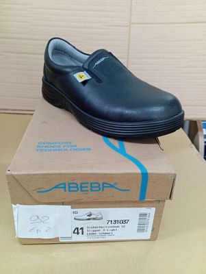 une chaussure noire posée sur une boîte