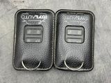 two black leather car key covers on a gray surface