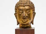 une image représentant une tête de Bouddha dorée posée sur un socle en bois