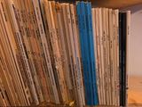 a lot of books that are stacked up on a shelf