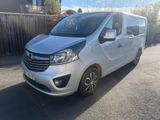 La camionnette argentée est garée dans la rue, devant une clôture en bois.