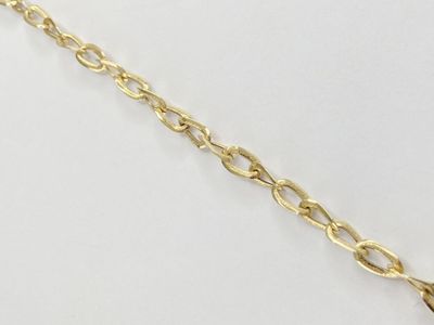 gros plan d'un bracelet en chaîne en or sur une surface blanche