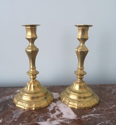 pair of brass candlesticks sitting on a marble table