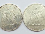 two silver coins, one of which has a statue of a woman and the other of which is a man