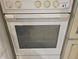 une cuisinière et un four dans une cuisine avec un carrelage au sol et des placards blancs