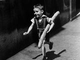 Photographie en noir et blanc d'un jeune garçon tenant une batte de baseball sur un trottoir