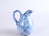 a small blue vase with a handle on a white surface