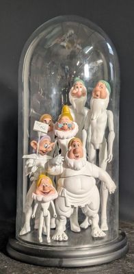 des figurines représentant un groupe de personnes sous un dôme en verre posé sur une table