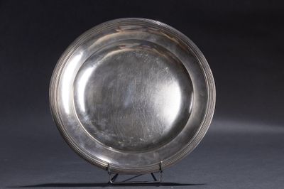 une assiette en argent posée sur un socle, sur fond noir