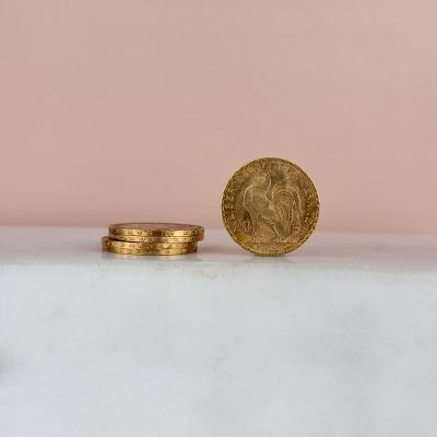 une pièce d'or posée sur une table blanche, à côté d'une pile de pièces