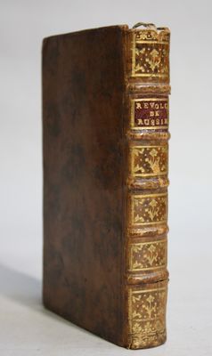 an old brown book with gold trim sitting on top of a white surface