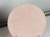 a pink plate sitting on a metal stand next to a wall