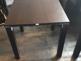 des tables et des chaises dans une pièce, avec un mur en arrière-plan