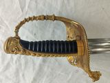 a gold sword with a black handle on a white background