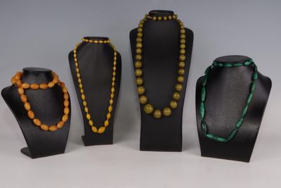 Trois colliers et deux bracelets sont exposés dans une vitrine.