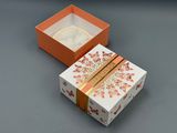 an orange and white box with a gold ribbon around it